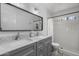 Modern bathroom with double sinks, sleek gray cabinets, a large mirror, and a tiled shower at 10759 N 101St St, Scottsdale, AZ 85260