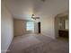 Bedroom featuring tan carpet, a ceiling fan, window, and ensuite bathroom entrance at 12547 W Pasadena Ave, Litchfield Park, AZ 85340