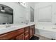 Well-lit bathroom with double sinks, a soaking tub, and classic fixtures, offering a relaxing atmosphere at 15515 N 165Th Ave, Surprise, AZ 85388