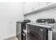 This laundry room features a gray, front-load washer and dryer, white cabinets and sleek flooring at 15515 N 165Th Ave, Surprise, AZ 85388