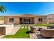 Backyard features patio with seating, outdoor kitchen, lush lawn area, and mature trees at 16860 W Soft Wind Dr, Surprise, AZ 85387