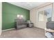 Cozy bedroom with green paneled accent wall, gray crib, and carpeted flooring at 16860 W Soft Wind Dr, Surprise, AZ 85387