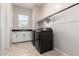 Well-lit laundry room features black appliances, tile floor, storage cabinets, and a utility sink at 16860 W Soft Wind Dr, Surprise, AZ 85387