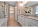 Bathroom featuring a glass shower and a double vanity with white cabinets and quartz countertops at 16935 W Sheridan St, Goodyear, AZ 85395