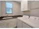Well-lit laundry room with a sink, ample counter space, and modern white washer and dryer at 16935 W Sheridan St, Goodyear, AZ 85395