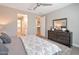 Bright main bedroom featuring a ceiling fan, a walk-in closet, and a dark wood dresser with a mirror at 16935 W Sheridan St, Goodyear, AZ 85395