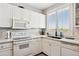 A bright and modern kitchen with white appliances and a charming view through plantation shutters at 1701 E Colter St # 443, Phoenix, AZ 85016