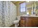 Well-lit bathroom boasts wood cabinets, decorative shower curtain and window with wood blind at 1786 S Seton Ave, Gilbert, AZ 85295
