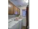Bright laundry room with upper cabinets, a window with blinds, and modern washer and dryer at 1786 S Seton Ave, Gilbert, AZ 85295