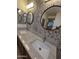 Bathroom featuring dual sinks, granite countertops, decorative backsplash, and a view of a bedroom through the mirror at 22508 W Antelope Trl, Buckeye, AZ 85326