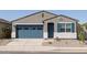 Inviting single-story home with a blue garage door and shutters, set against a grey stucco exterior with desert landscaping at 37153 W Prado St, Maricopa, AZ 85138