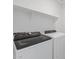 Well-lit laundry room showcasing a modern washer and dryer with a shelf above, offering convenience and functionality at 37153 W Prado St, Maricopa, AZ 85138
