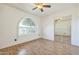 Bedroom with wood floors, ceiling fan, an arched window, and mirrored closet doors at 3833 W Phelps Rd, Phoenix, AZ 85053