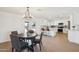 Dining area with wood table, chairs and lighting fixture, with a view to an open-concept kitchen with white cabinets at 4117 W Camino Acequia Ave, Phoenix, AZ 85051