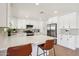 Bright kitchen with stainless steel appliances, white cabinets, an island with a quartz countertop, and modern bar stools at 4117 W Camino Acequia Ave, Phoenix, AZ 85051