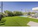 Backyard features artificial grass, a pool, a dining table with seating, and privacy hedges at 4120 N 44Th Pl, Phoenix, AZ 85018