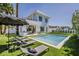 Beautiful pool area with lounge chairs, umbrellas, and a modern white home in the background at 4120 N 44Th Pl, Phoenix, AZ 85018