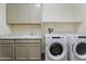 Well-equipped laundry room with a utility sink, cabinetry, and modern washer and dryer units at 7180 W Tombstone Trl, Peoria, AZ 85383