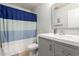Well-lit bathroom features a gray vanity with white sink and modern fixtures plus a blue and white striped shower curtain at 7317 S 37Th Gln, Phoenix, AZ 85041
