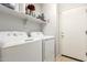 Laundry room with side-by-side washer and dryer, overhead shelving, and a white door for convenient access at 7317 S 37Th Gln, Phoenix, AZ 85041