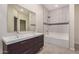 Modern bathroom featuring double sinks, a vanity, and a tiled shower-tub combo at 802 W Buist Ave, Phoenix, AZ 85041