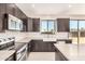 Well-lit kitchen with stainless appliances, dark cabinets, white backsplash, a large window, and an island at 802 W Buist Ave, Phoenix, AZ 85041