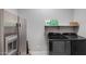Convenient laundry room featuring a front-load washer/dryer, storage shelf, and a modern, stainless steel refrigerator at 9723 W Patrick Ln, Peoria, AZ 85383