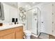 Clean bathroom with glass shower, wooden vanity, and hexagon mirror detail at 14393 W Wethersfield Rd, Surprise, AZ 85379