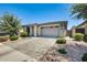 Single-story home featuring manicured landscaping, a stone-accented facade, and a two-car garage at 14393 W Wethersfield Rd, Surprise, AZ 85379