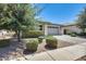 Well-kept single-story home featuring a stone facade, neatly landscaped front yard, and two-car garage at 14393 W Wethersfield Rd, Surprise, AZ 85379