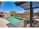 Beautiful pool and spa area with a modern pergola, lush landscaping, a brick wall, and outdoor seating at 14393 W Wethersfield Rd, Surprise, AZ 85379