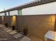 Private side yard with stone pavers, potted plants, and wall lighting, offering a serene outdoor space at 14393 W Wethersfield Rd, Surprise, AZ 85379