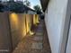 Cozy side yard features a stone paver pathway and illuminated landscaping along a privacy wall at 14393 W Wethersfield Rd, Surprise, AZ 85379
