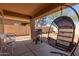 Relaxing covered back porch area with a grill, table, chairs, and a cozy egg-shaped chair at 14436 N 162Nd Ln, Surprise, AZ 85379