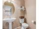 Bathroom with a round mirror, a pedestal sink, and a toilet at 14436 N 162Nd Ln, Surprise, AZ 85379