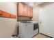 Functional laundry room with overhead cabinets, modern washer and dryer, and tiled floor at 14436 N 162Nd Ln, Surprise, AZ 85379
