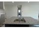 Modern kitchen island with stainless steel sink, granite countertops, and a view of the hallway at 38070 W Frascati Ave, Maricopa, AZ 85138
