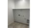 Bright laundry room with tile flooring, hookups, and convenient shelving for storage and organization at 38070 W Frascati Ave, Maricopa, AZ 85138