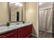 Modern bathroom with a red vanity cabinet, granite countertop, and gray wood-look flooring at 3946 N 112Th Ave, Avondale, AZ 85392