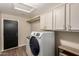 Well-lit laundry room with white washer and dryer, overhead cabinets, and durable flooring at 3946 N 112Th Ave, Avondale, AZ 85392
