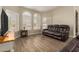 Spacious living room featuring a comfortable dark brown leather sofa and wood-look tile floors at 3946 N 112Th Ave, Avondale, AZ 85392