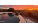 Relaxing pool with landscaped border set against a colorful sunset sky at 5306 N 188Th Ln, Litchfield Park, AZ 85340