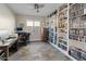 Spacious home office featuring custom built-in shelving, a ceiling fan, and wood-look tile flooring at 549 E Balao Dr, Phoenix, AZ 85085