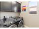Laundry room featuring modern Samsung washer and dryer, overhead cabinets, and a painted sunset on the wall at 549 E Balao Dr, Phoenix, AZ 85085