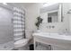 A bathroom with a vanity with a vessel sink, mirror, toilet, and tiled shower at 6216 W Poinsettia Dr, Glendale, AZ 85304