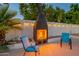 Cozy outdoor brick fireplace in a walled patio area, illuminated by overhead string lights at 6216 W Poinsettia Dr, Glendale, AZ 85304
