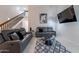 Modern living area showcasing vaulted ceilings, stylish grey sofas, tile flooring, and a staircase at 6216 W Poinsettia Dr, Glendale, AZ 85304