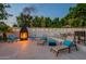 Relaxing backyard patio with fireplace, lounge chairs, and seating area under string lights at 6216 W Poinsettia Dr, Glendale, AZ 85304