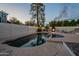 Sparkling pool with a relaxing spa, accented by string lights and a fire pit for a serene outdoor experience at 6216 W Poinsettia Dr, Glendale, AZ 85304