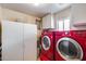 Well-lit laundry room with red washer and dryer units and ample storage cabinets at 7210 W Caron Dr, Peoria, AZ 85345